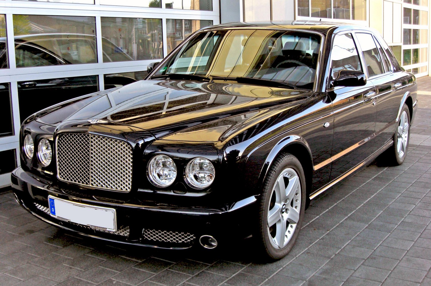 Front and side view of luxury sedan with mesh grille and round headlights