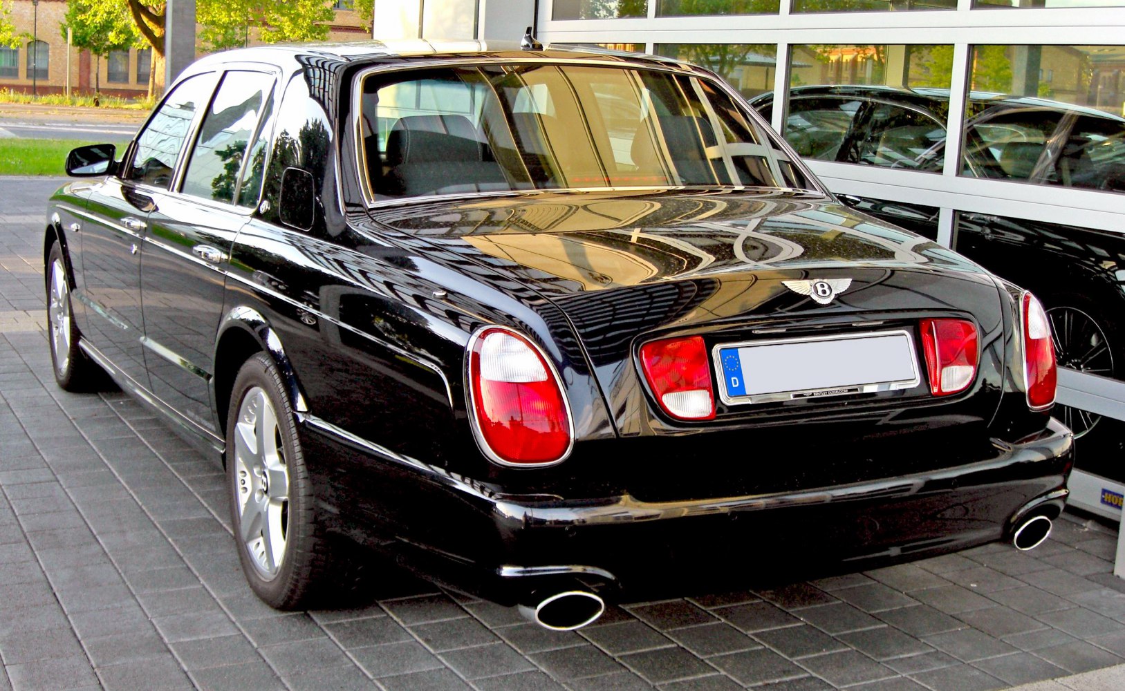 Rear view of black luxury sedan with distinctive taillights and twin exhaust pipes