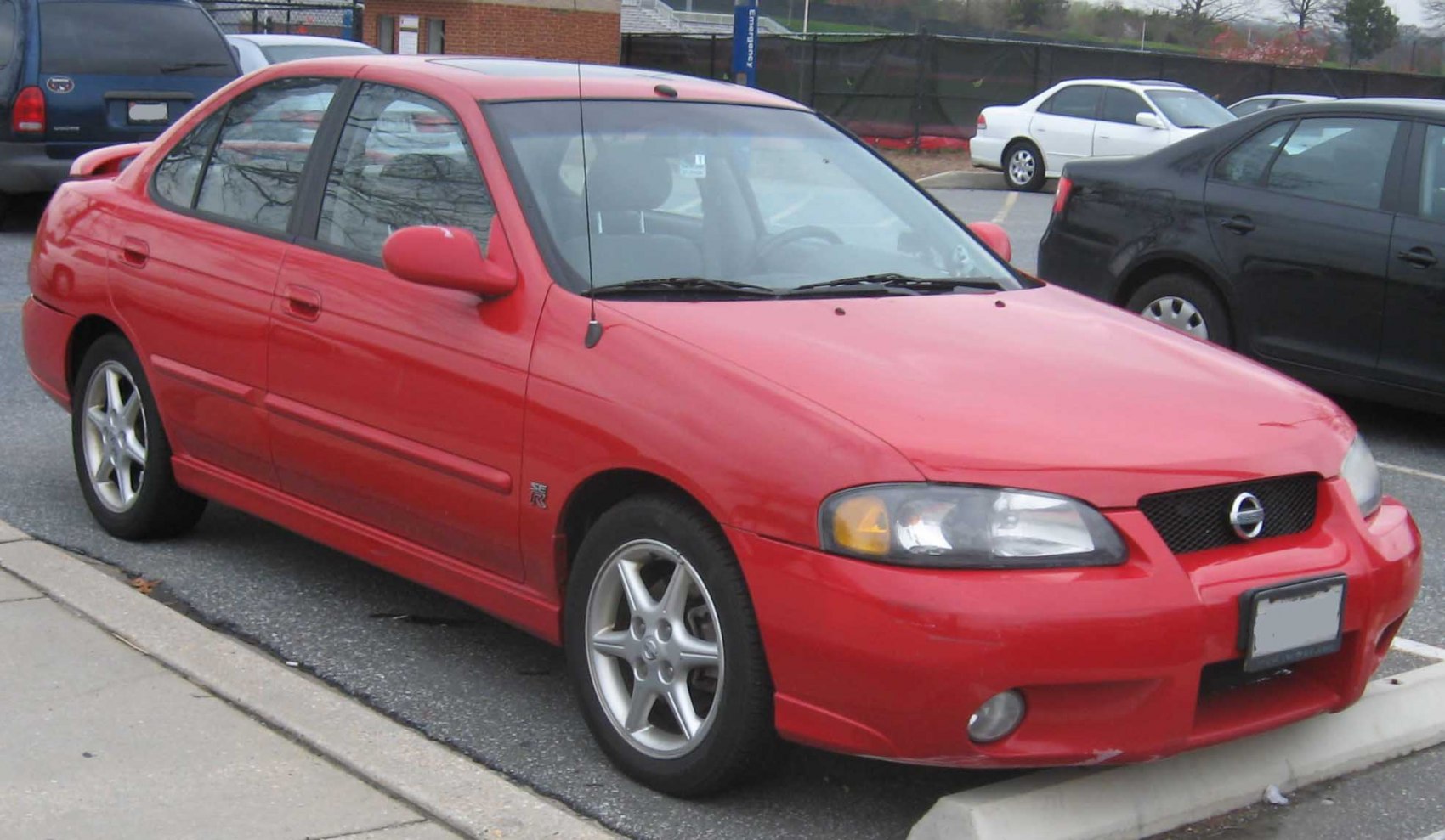 Red compact sporty sedan with alloy wheels and front fog lights
