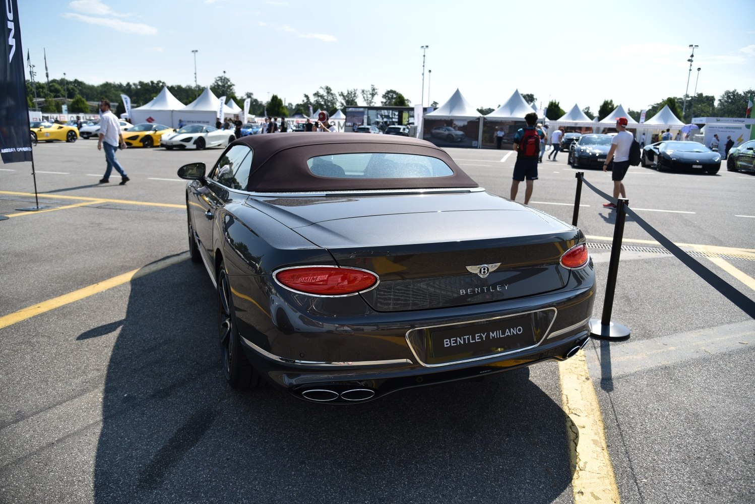 Rear view of a convertible with soft top, oval taillights, and dual exhaust pipes.