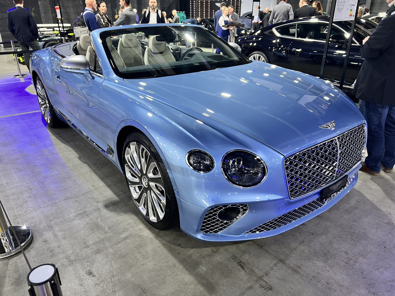 Luxury blue convertible with mesh grille and multi-spoke wheels