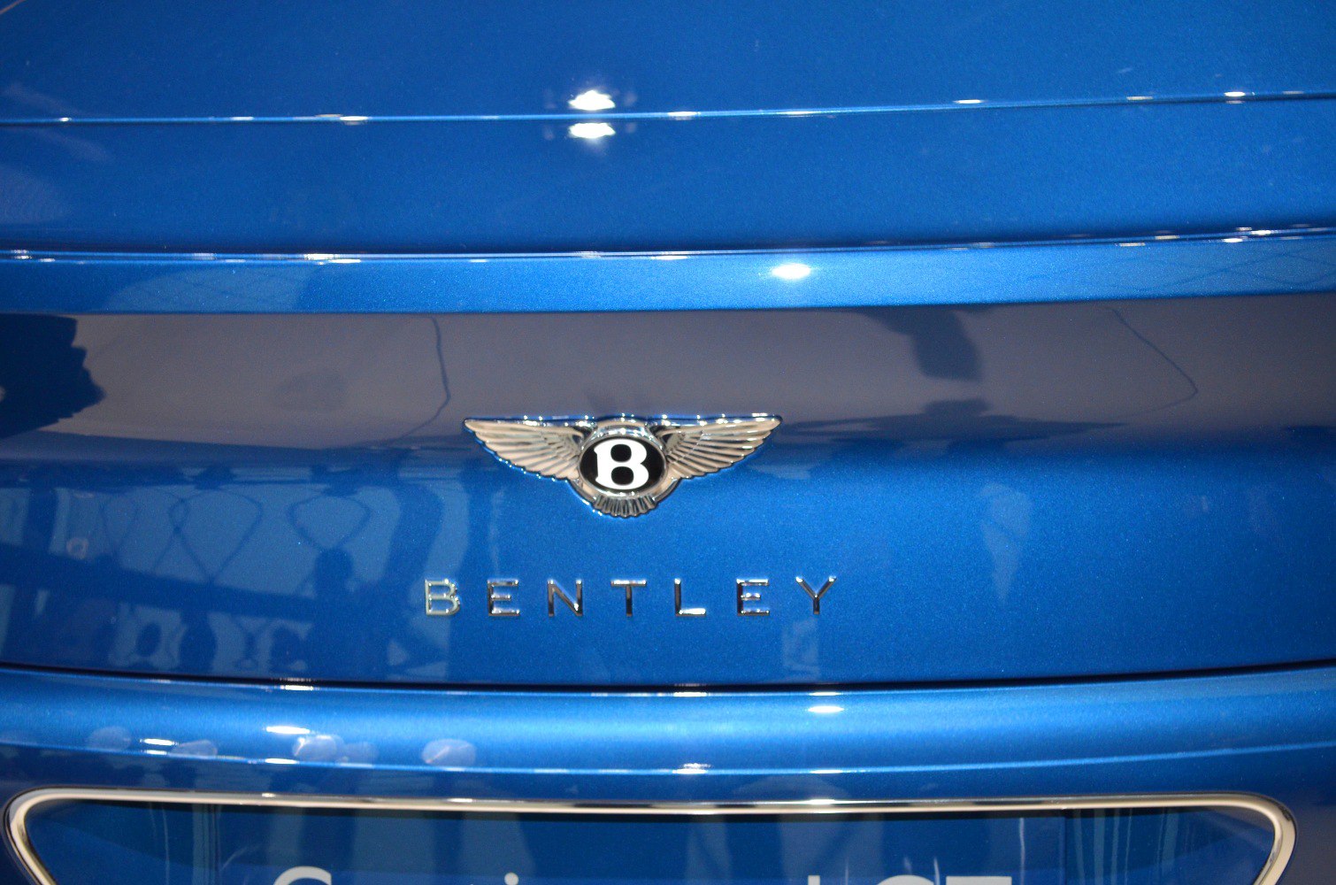 Close-up of a luxury car's rear emblem and badge on blue paint