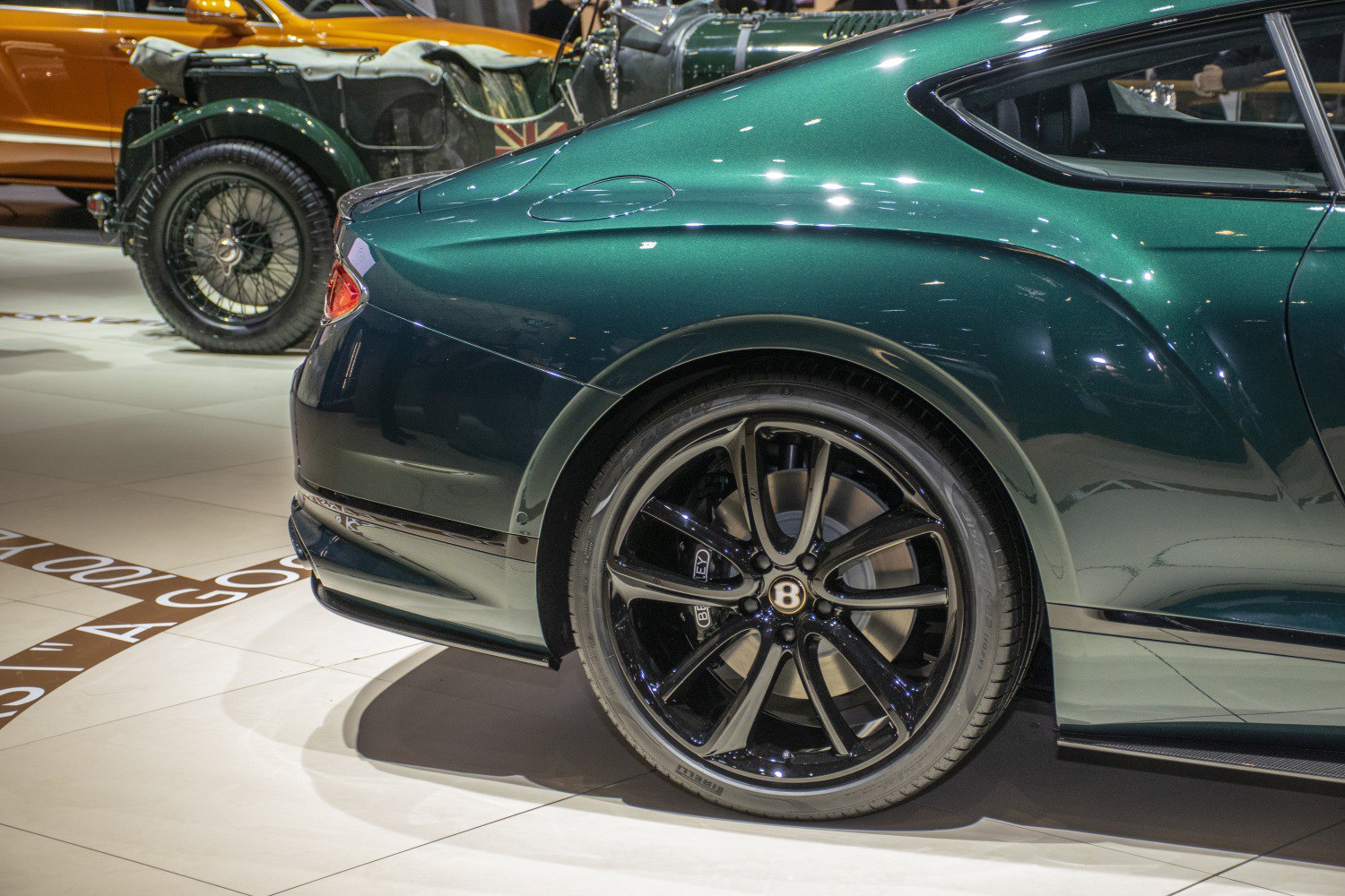 Rear wheel with black alloy rim and curved rear body panel in glossy green.