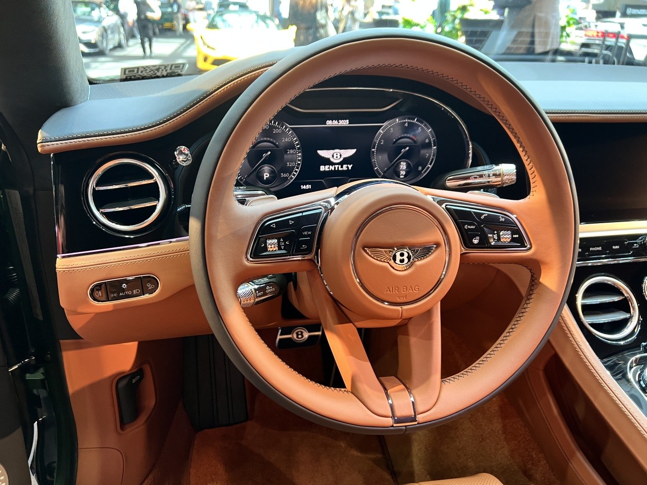 Tan leather steering wheel with control buttons and digital instrument cluster