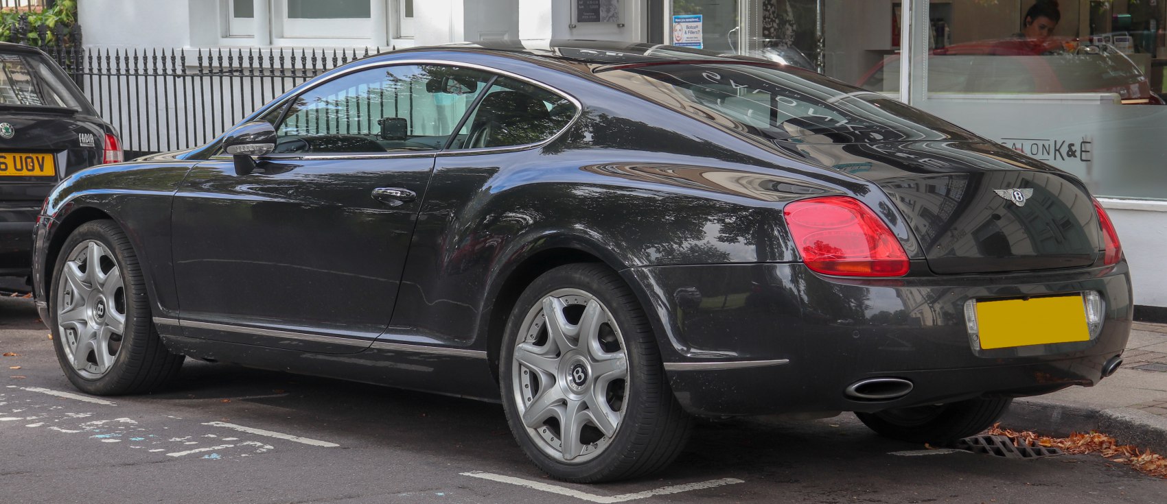Rear three-quarter view of a sleek luxury coupe showing tail lights and alloy wheels