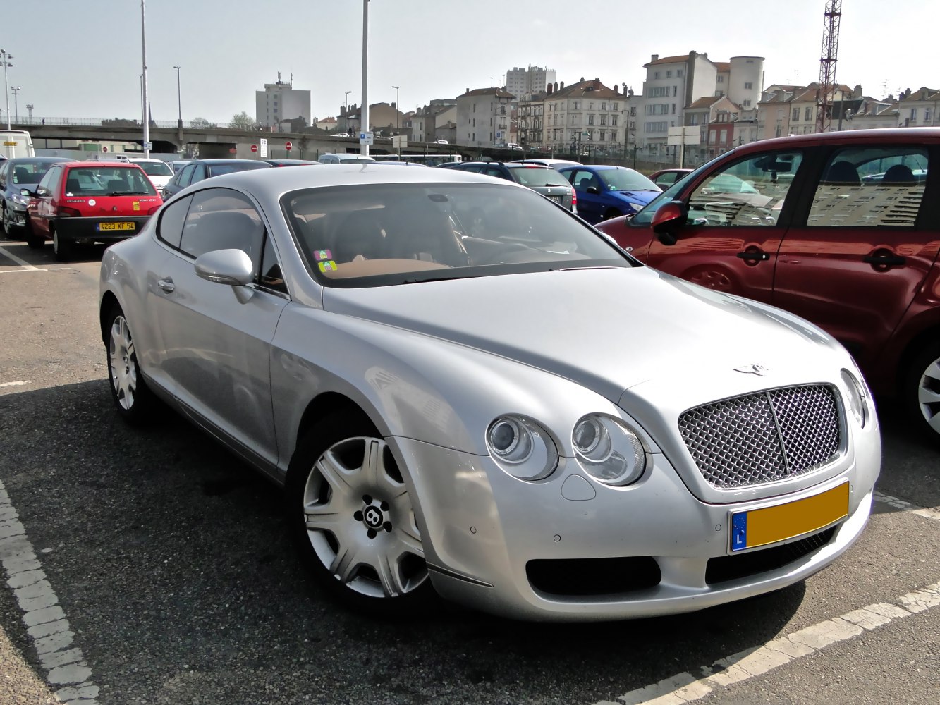 Silver luxury coupe with quad round headlights and mesh grille