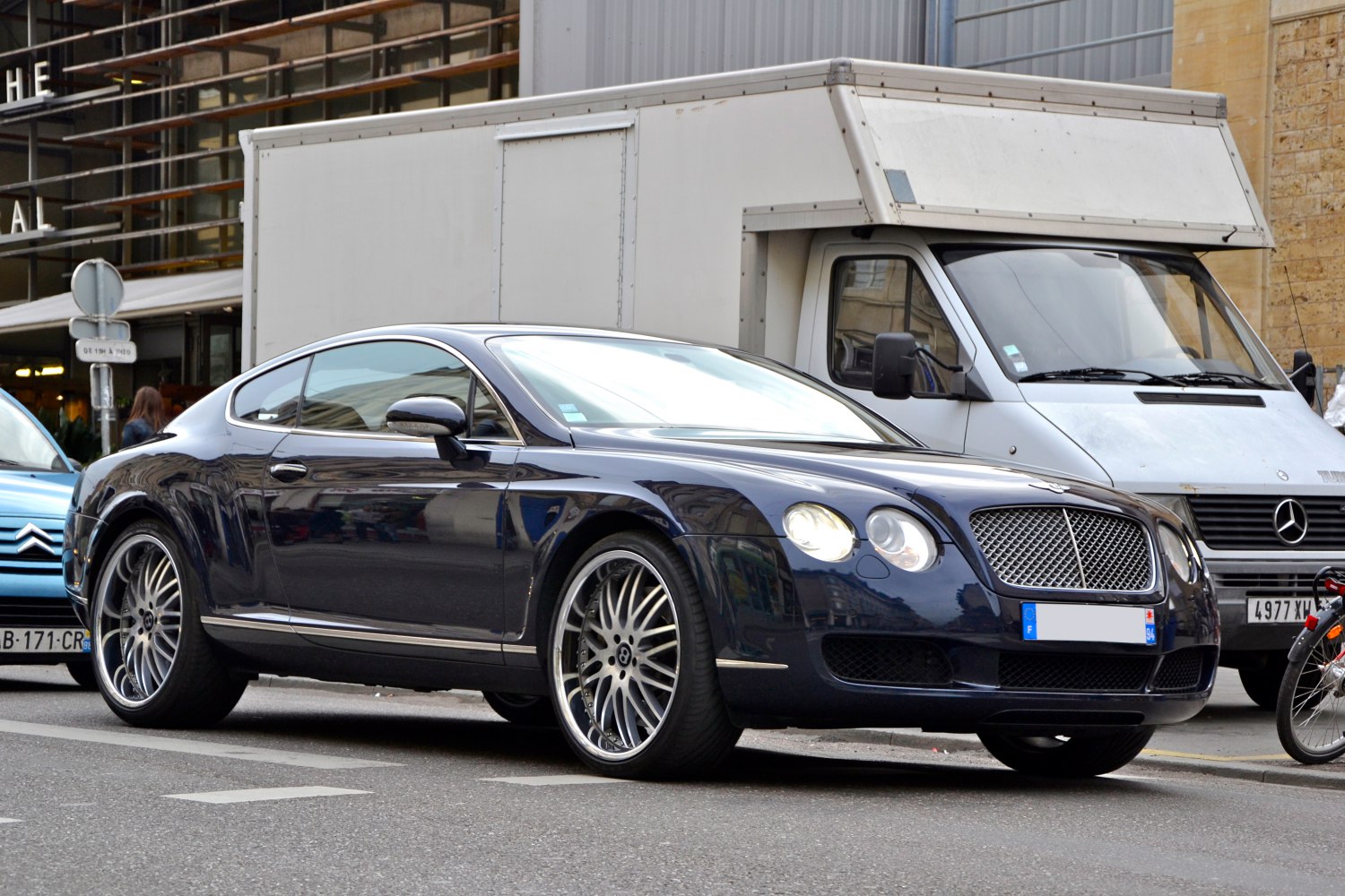 Luxury black grand tourer with mesh grille and multi-spoke alloy wheels