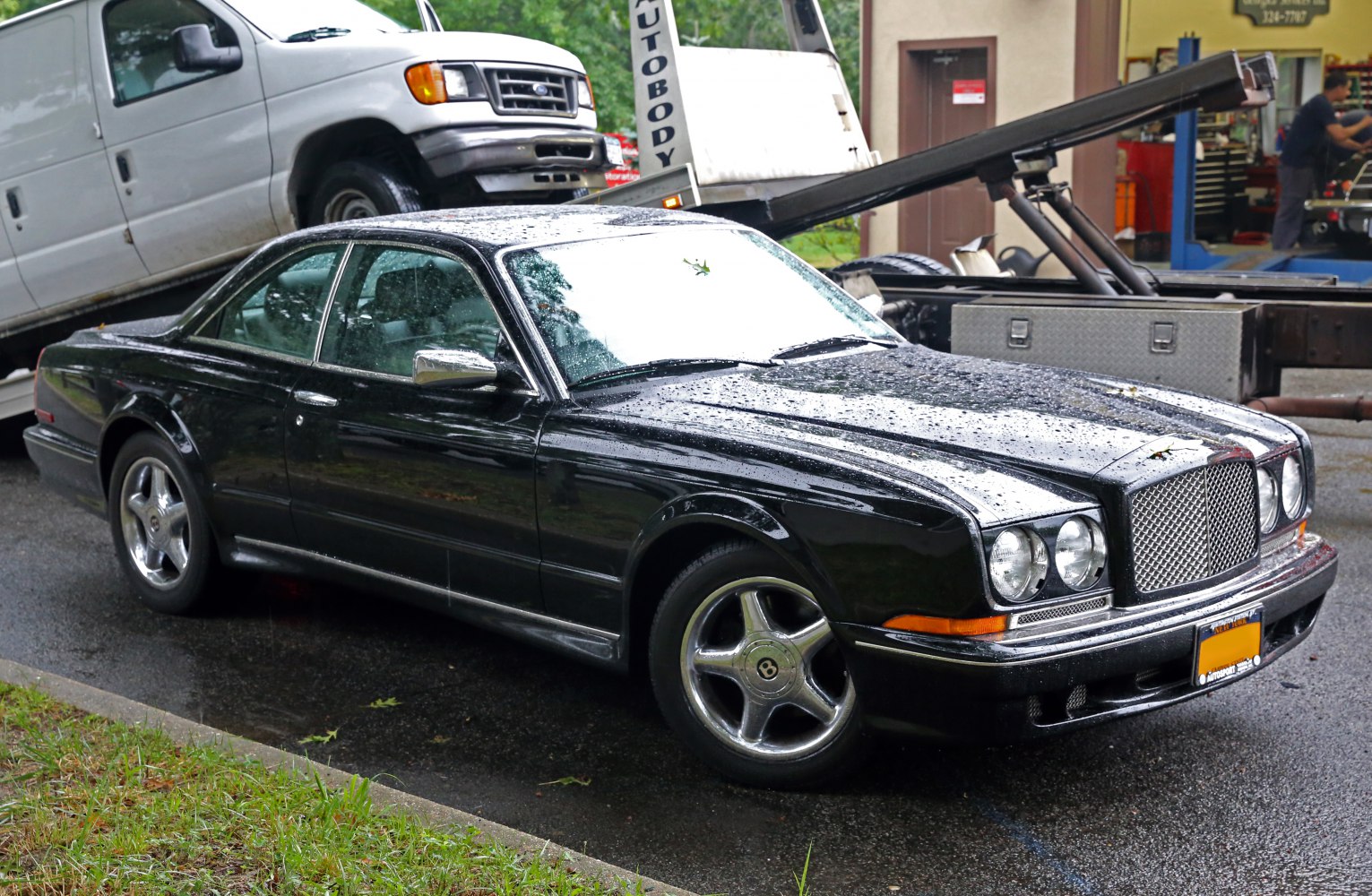 Luxury coupe with chrome mesh grille and alloy wheels in rainy setting