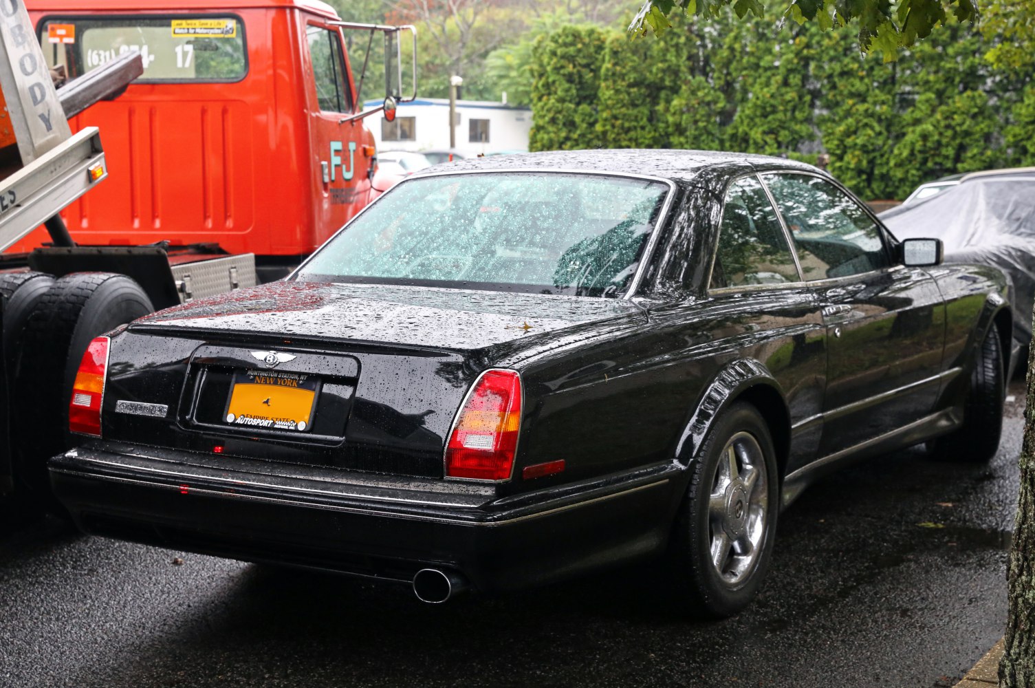 Rear view of luxury coupe with vertical tail lights and chrome exhaust