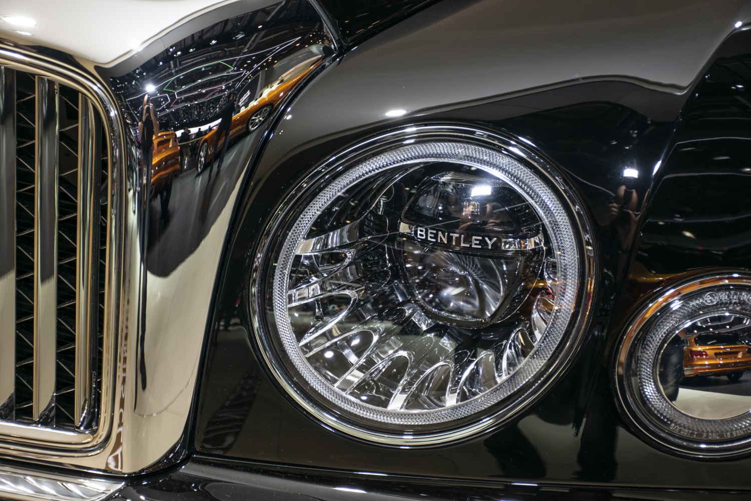 Round headlight and chrome grille close-up with reflections