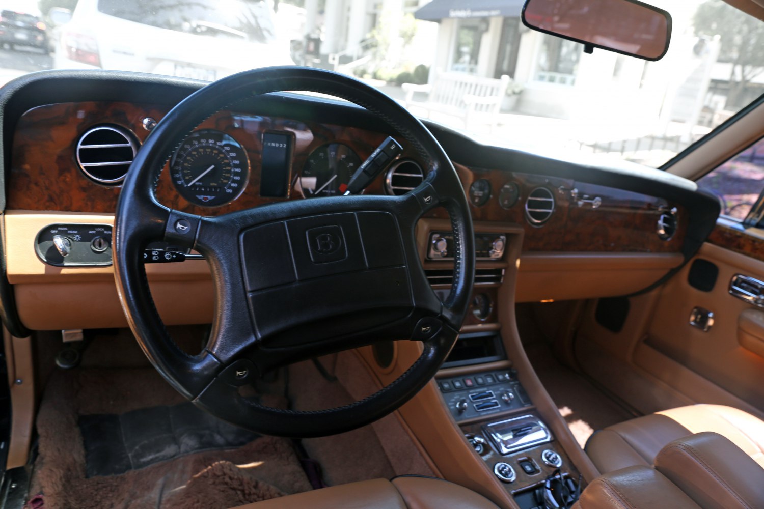 Classic luxury steering wheel and dashboard with wood panel trim.