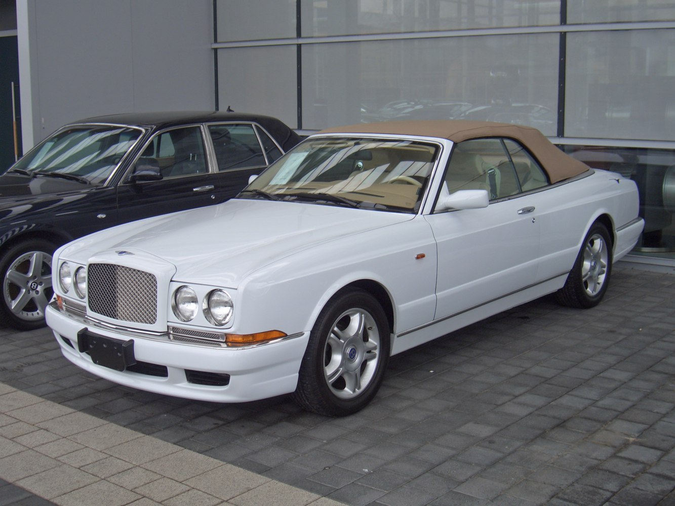 White luxury convertible with beige soft top and classic front grille