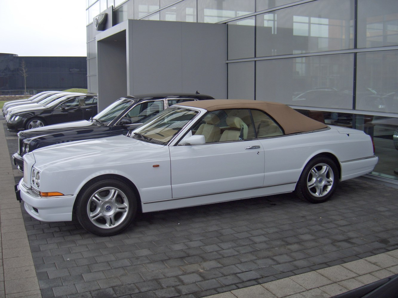 White convertible with tan soft top and luxury design lines.