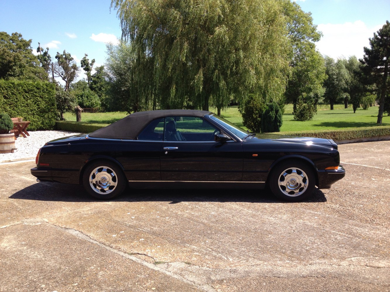 Classic convertible with soft top roof and polished alloy wheels in side view