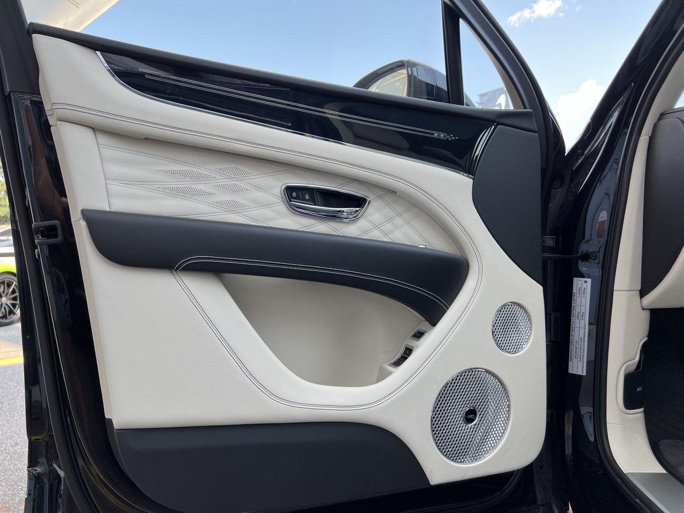 Luxury car door interior with leather, stitching, and dual speaker audio system