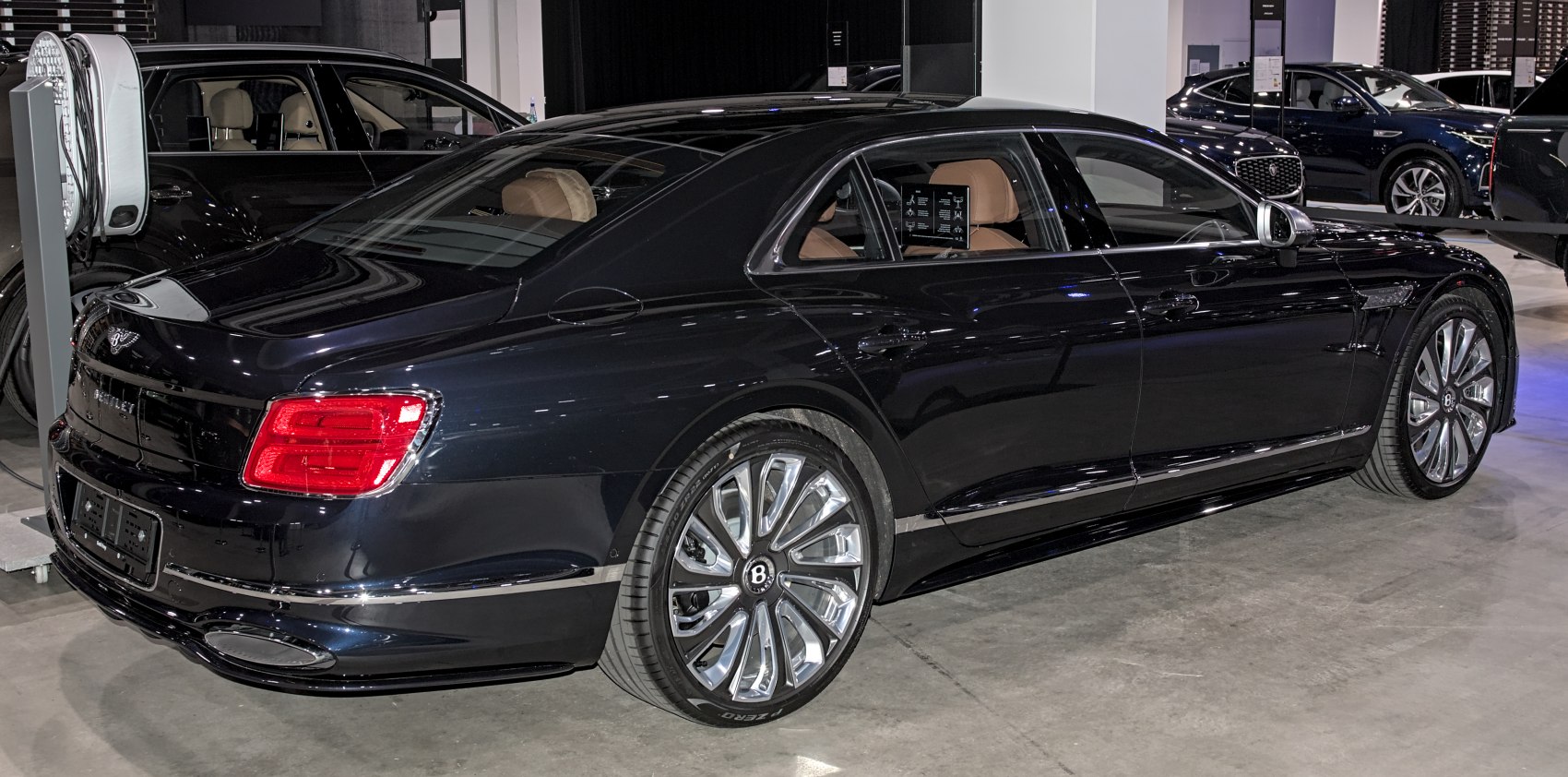 Luxury sedan side-rear view with taillights and alloy wheels