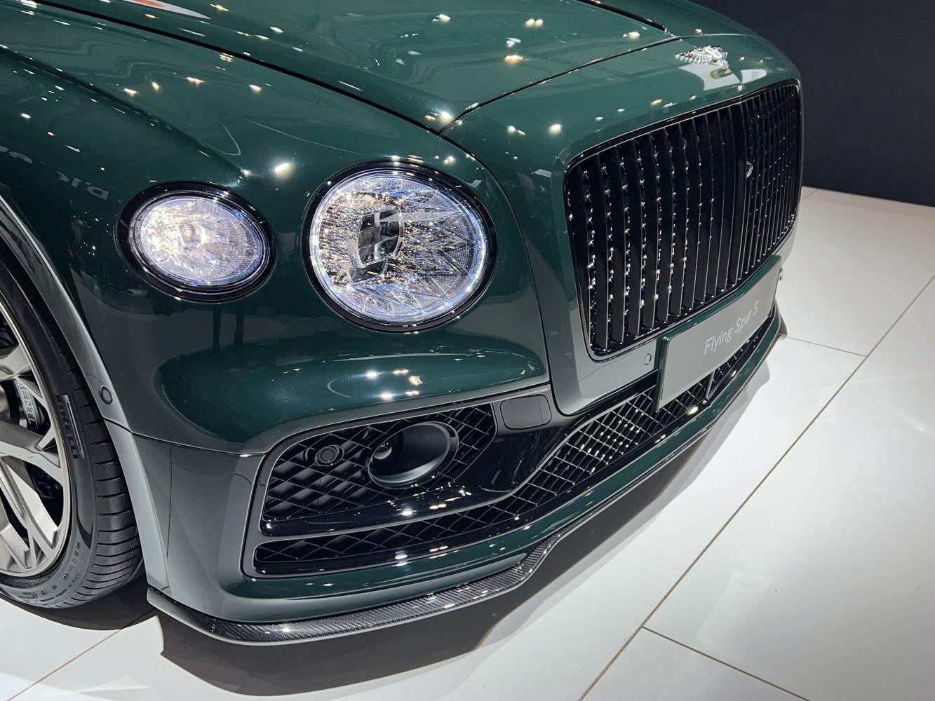Close-up of dual round headlights and black grille on a luxury vehicle.