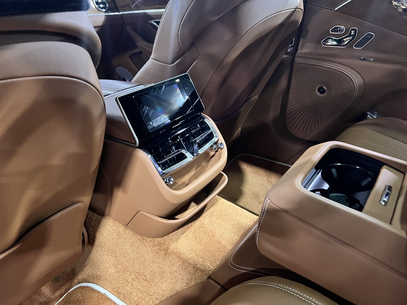 Touchscreen control panel and air vents in brown leather rear interior