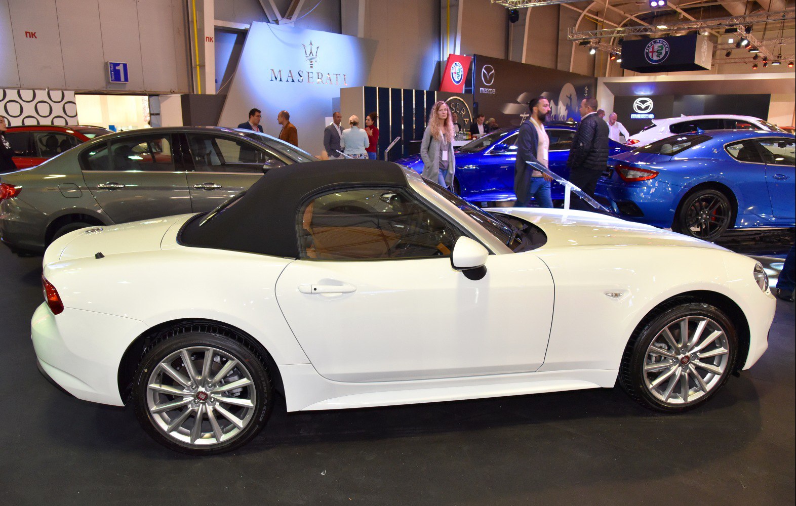 White convertible with black soft top and alloy wheels side profile