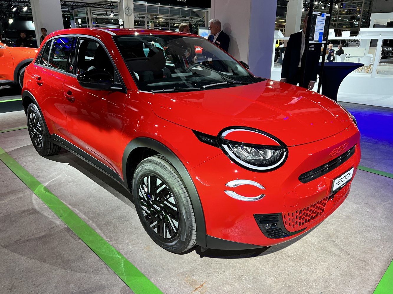 Red compact electric SUV with round headlights and sporty front grille