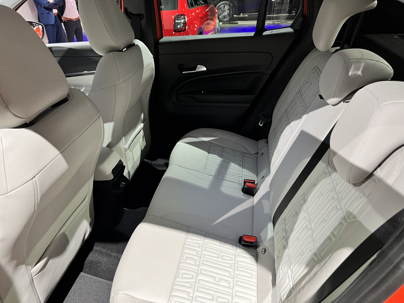 Rear seat interior with white upholstery and detailed stitching.