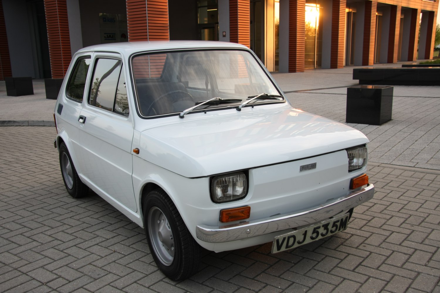 Vintage white compact car with square headlights and chrome bumper