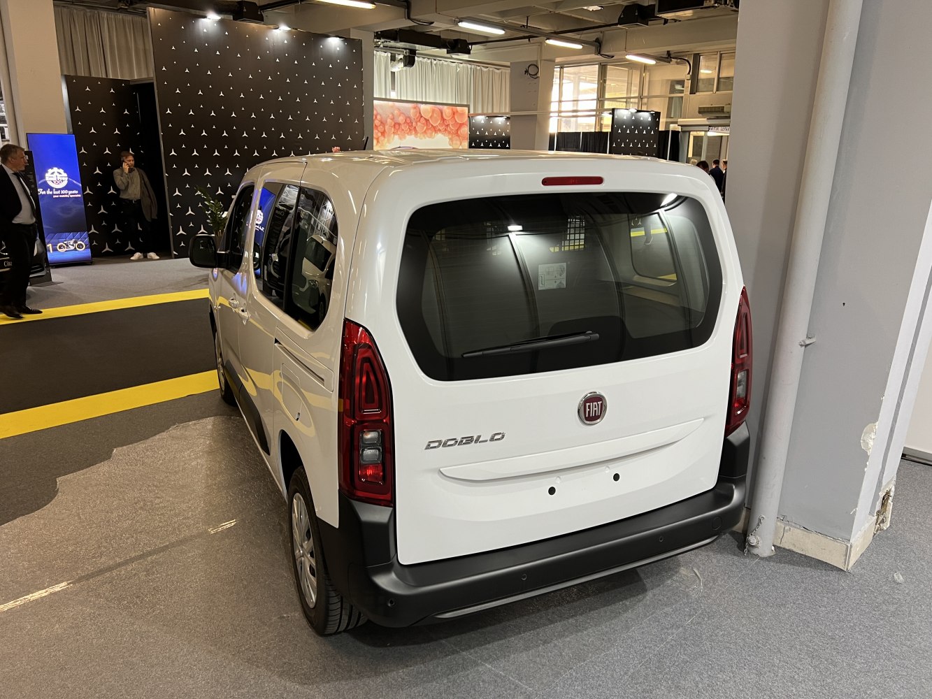 Rear view of white van with distinctive tail lights and rear window.