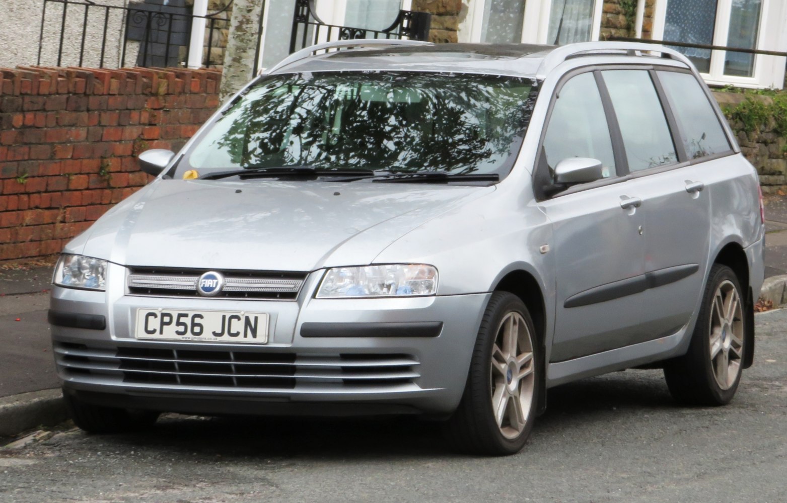 Front and side view of a silver compact wagon with roof rails and alloy wheels