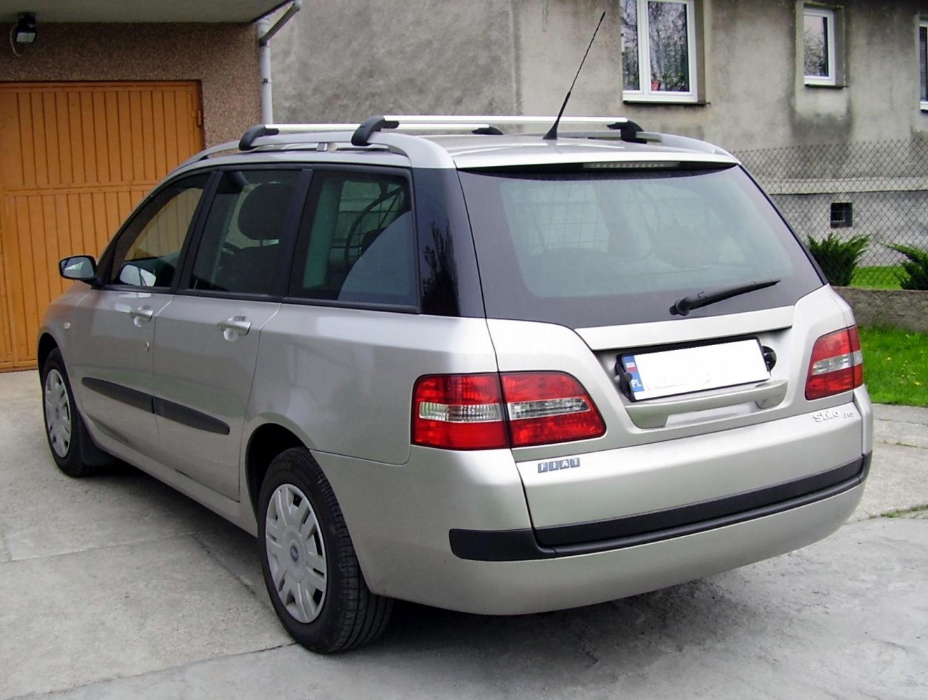 Rear view of a silver station wagon with roof rails and distinctive taillights.