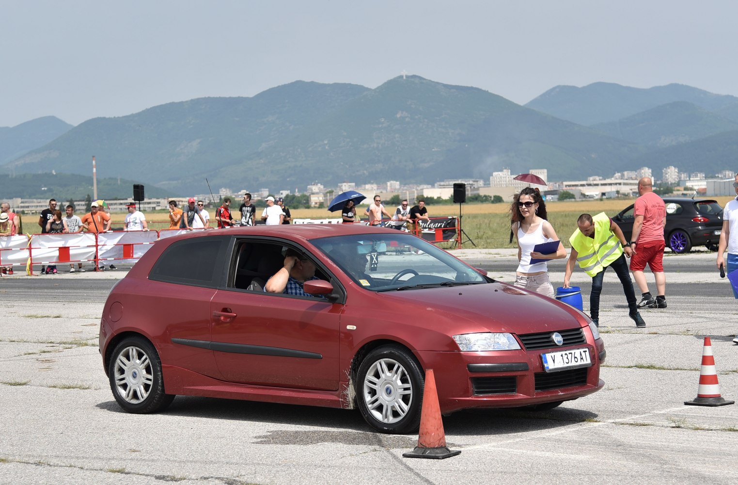 Red 3-door hatchback navigating an outdoor cone course