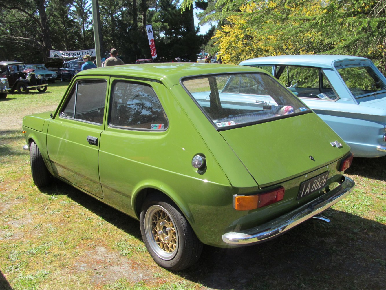 Green two-door hatchback with gold alloy wheels and chrome bumper