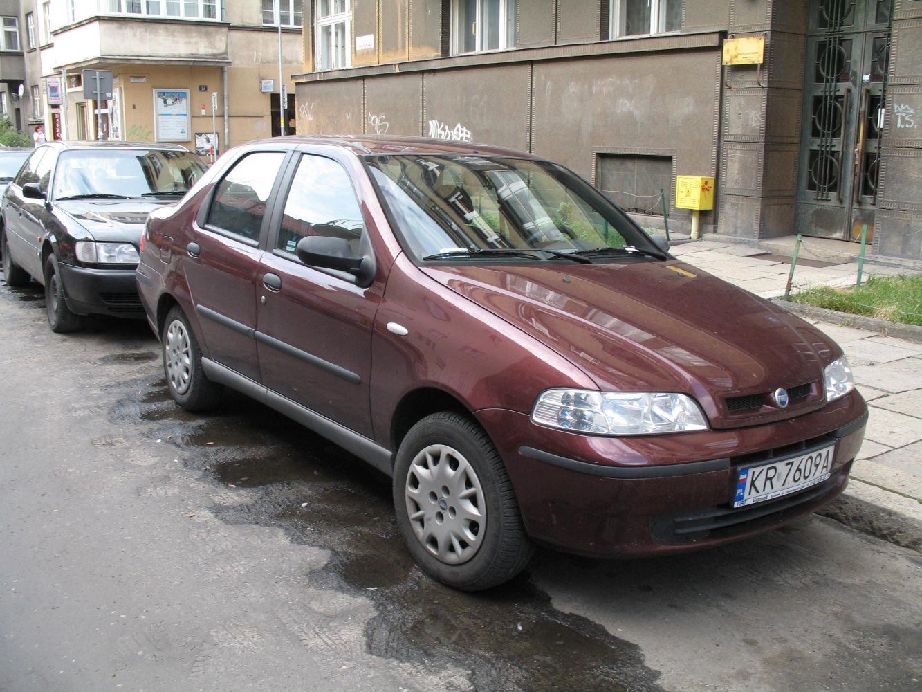 Front and side view of maroon sedan parked on street