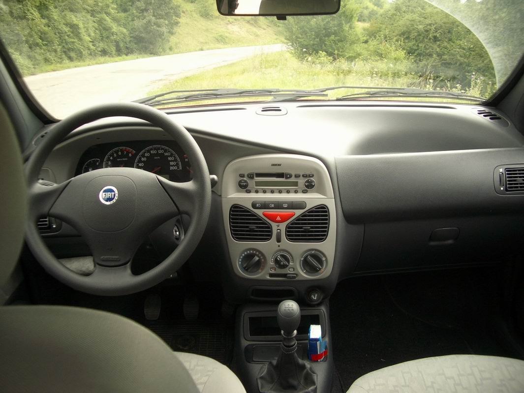 Dashboard and steering wheel with manual gear stick and center console.