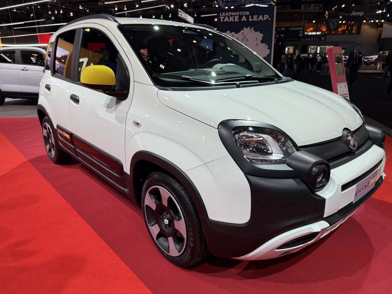 White compact vehicle with yellow side mirror and distinctive front lighting