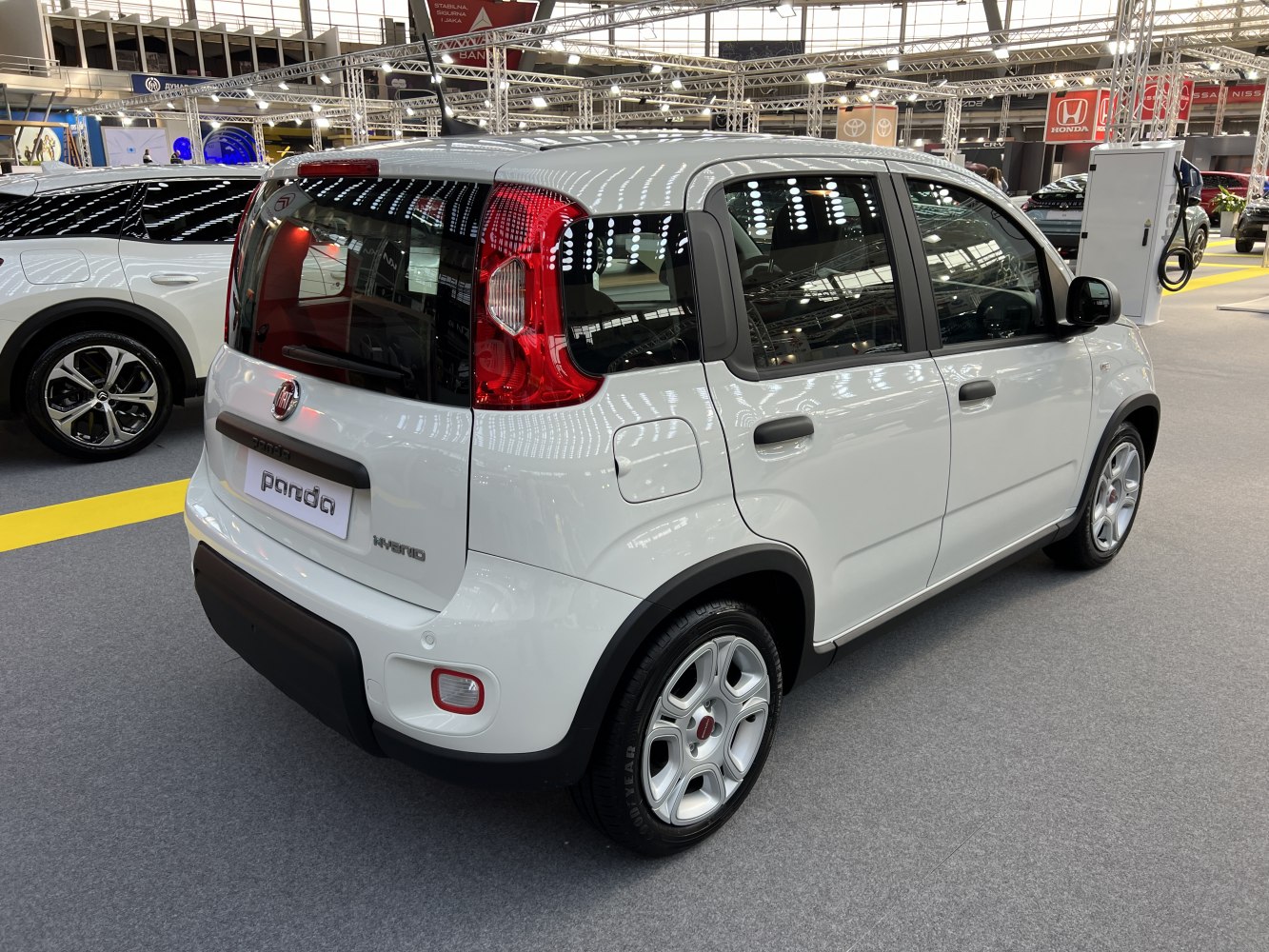 Rear-side view of a small white hatchback with hybrid badge and distinct rear lights