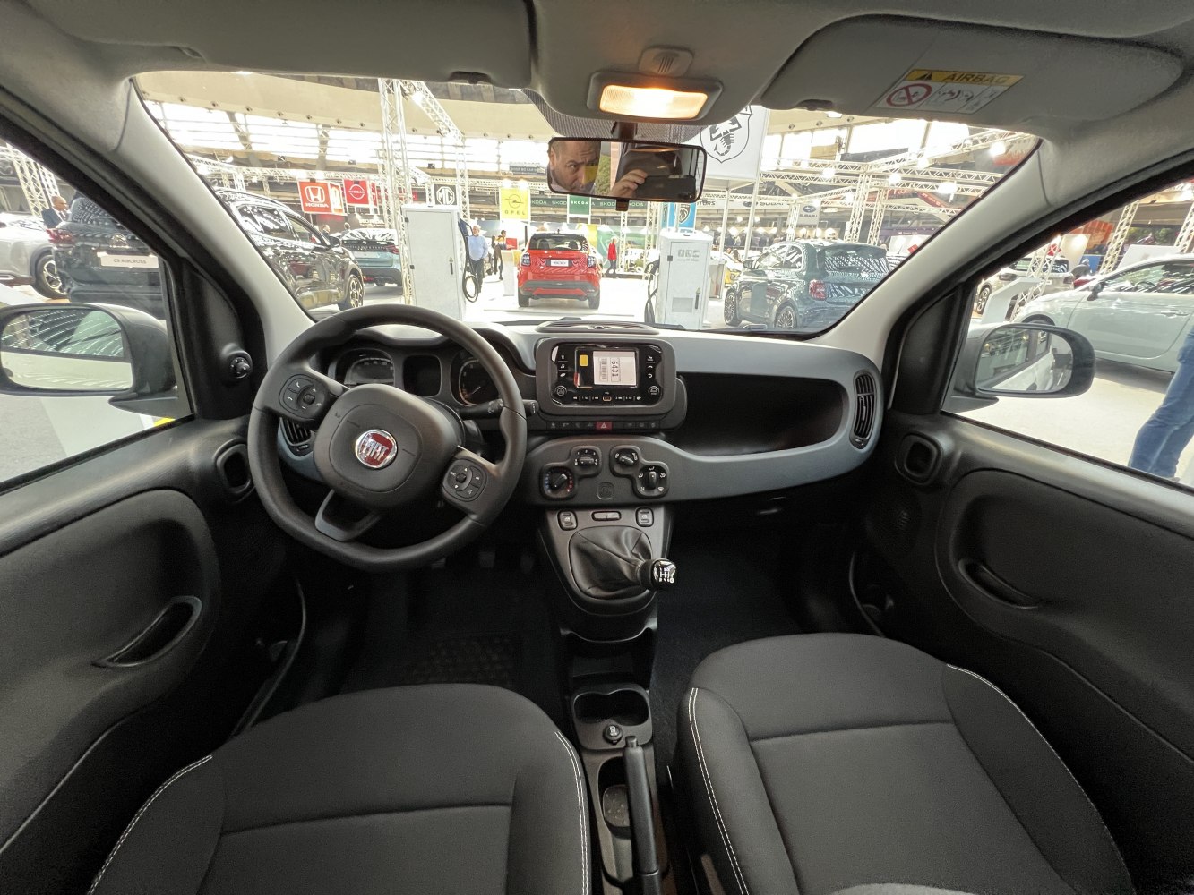 Dashboard, steering wheel, and manual gear shift inside compact car