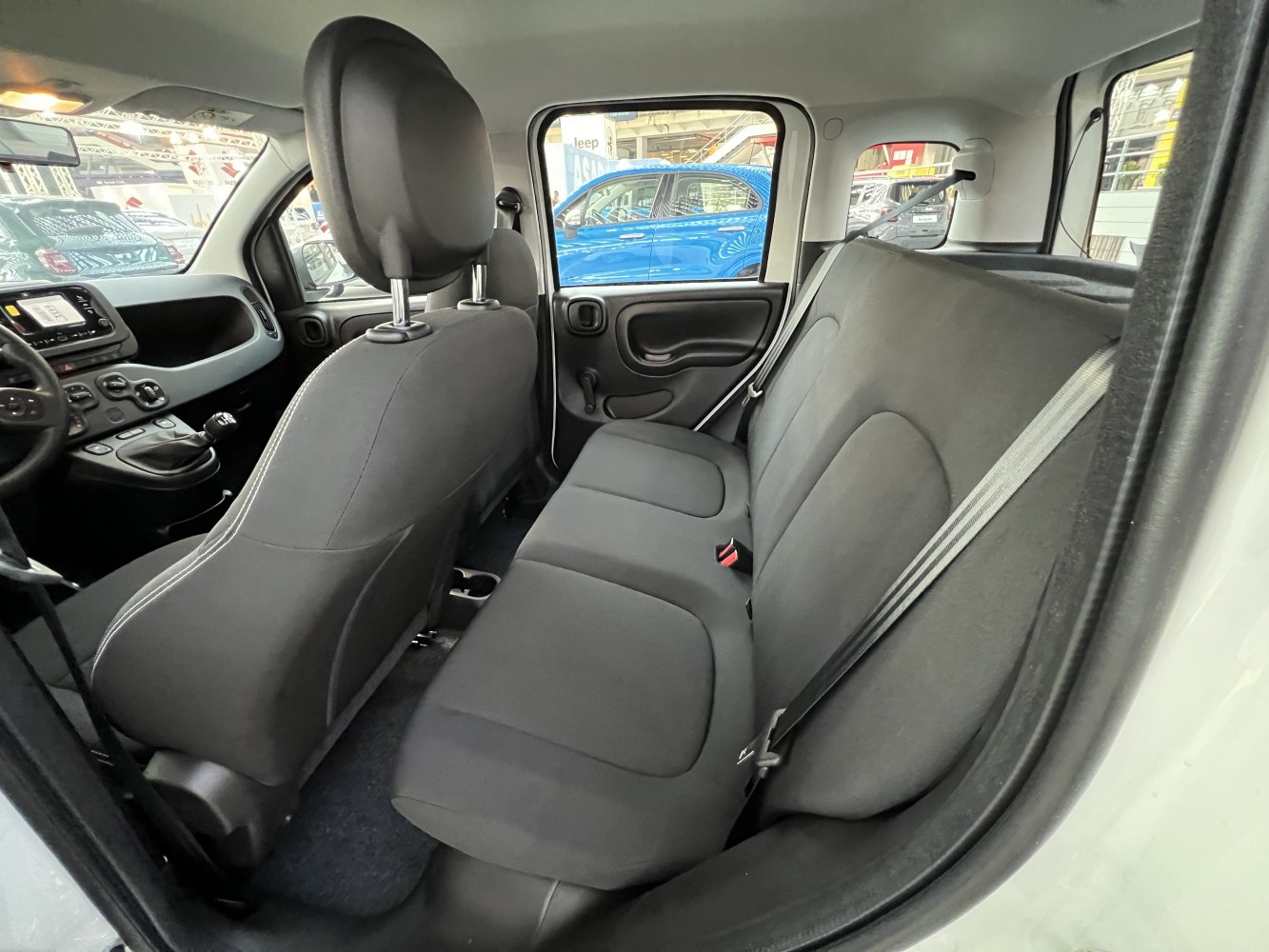 Rear bench seats and manual window crank in compact car interior