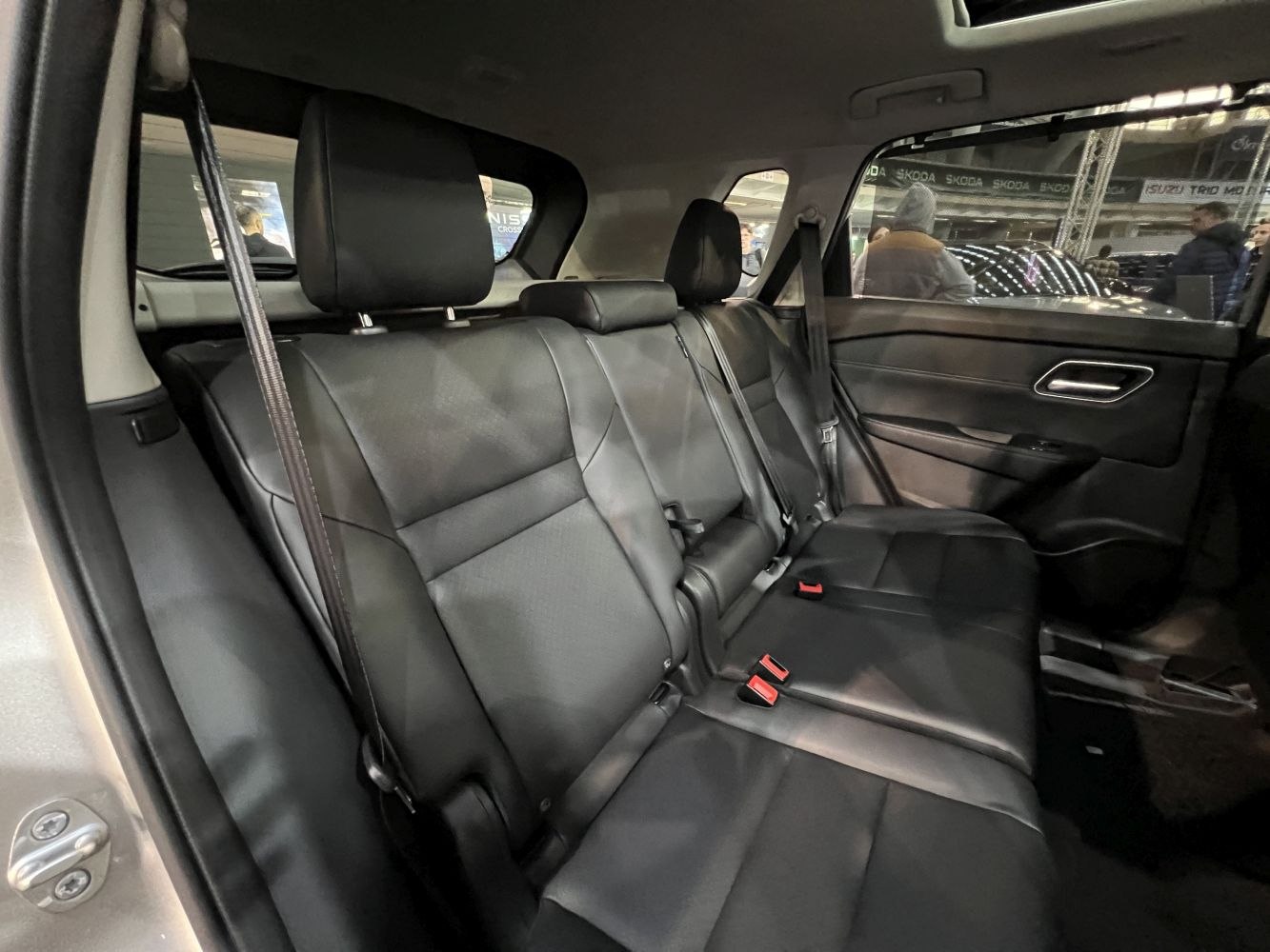 Rear black leather seats with headrests and door panel inside vehicle