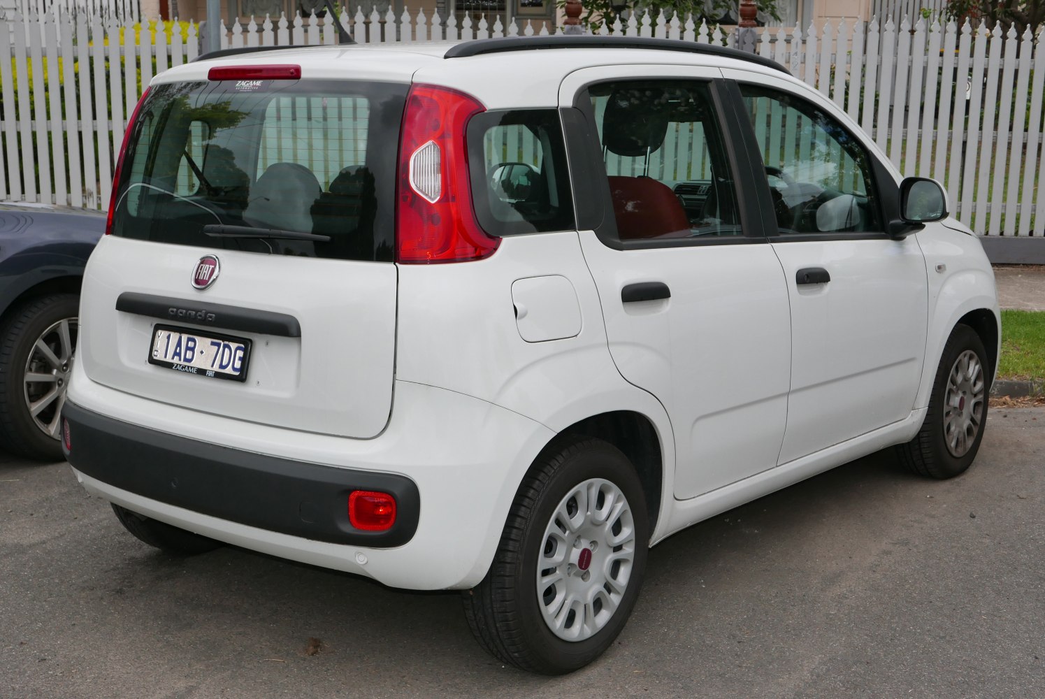Rear and side view of a small white hatchback with distinctive tail lights and compact design.