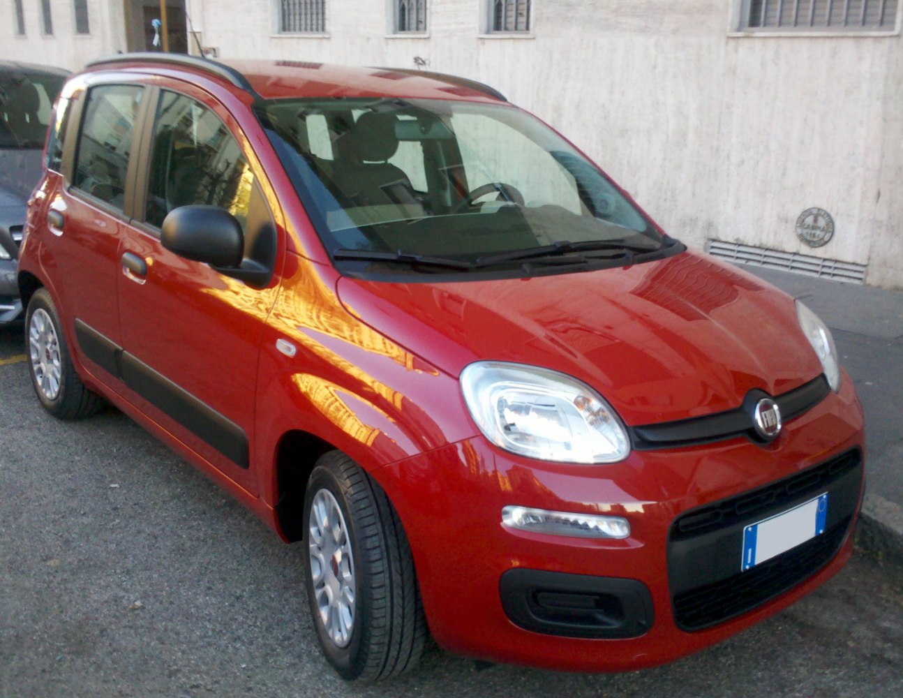 Compact car with roof rails and rounded headlights in urban setting