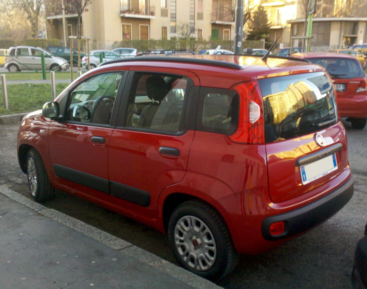Red compact hatchback rear side with black trim and roof rails
