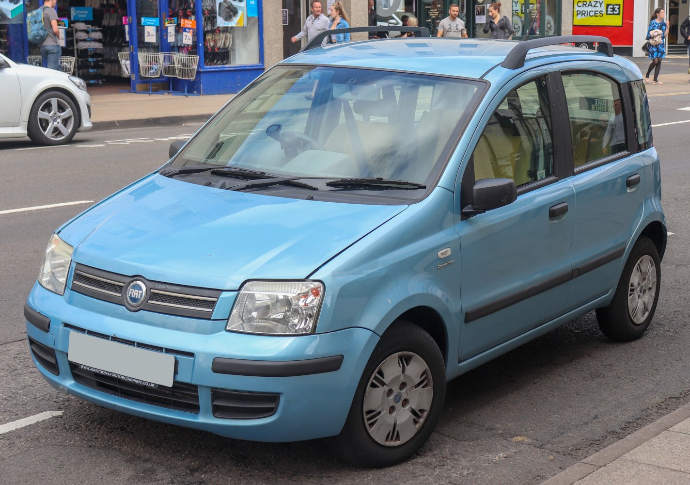 Compact car with rounded headlights and roof rails on a city street