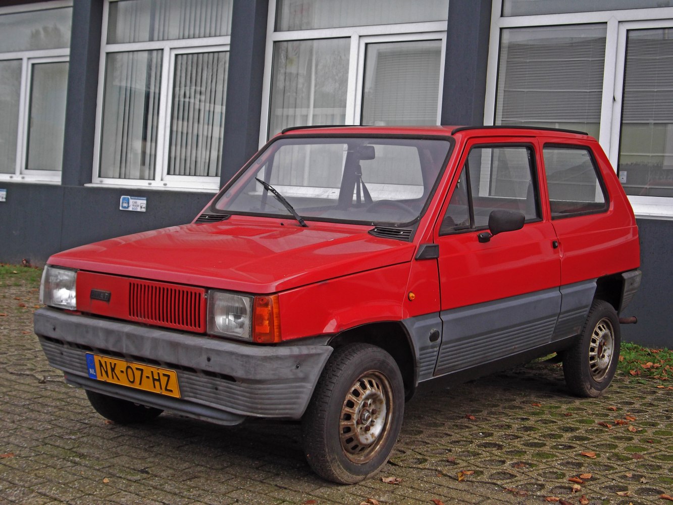 Boxy red compact hatchback with grey lower body trim and square headlights