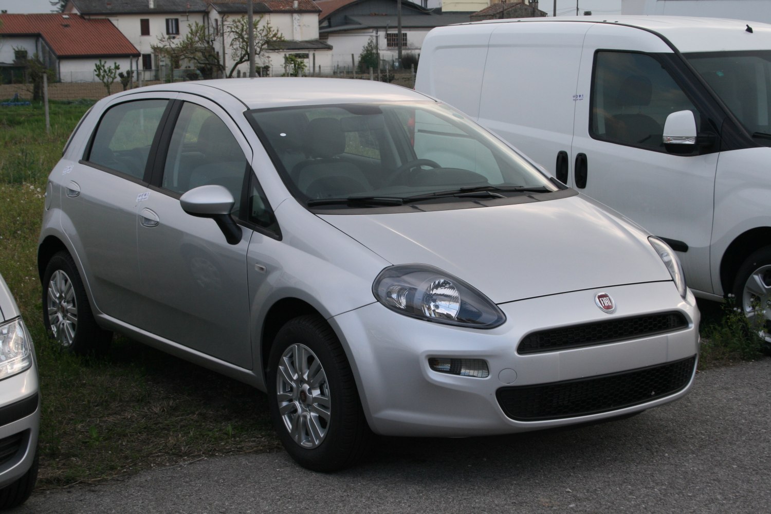 Silver compact hatchback with distinctive headlights and black honeycomb grille.