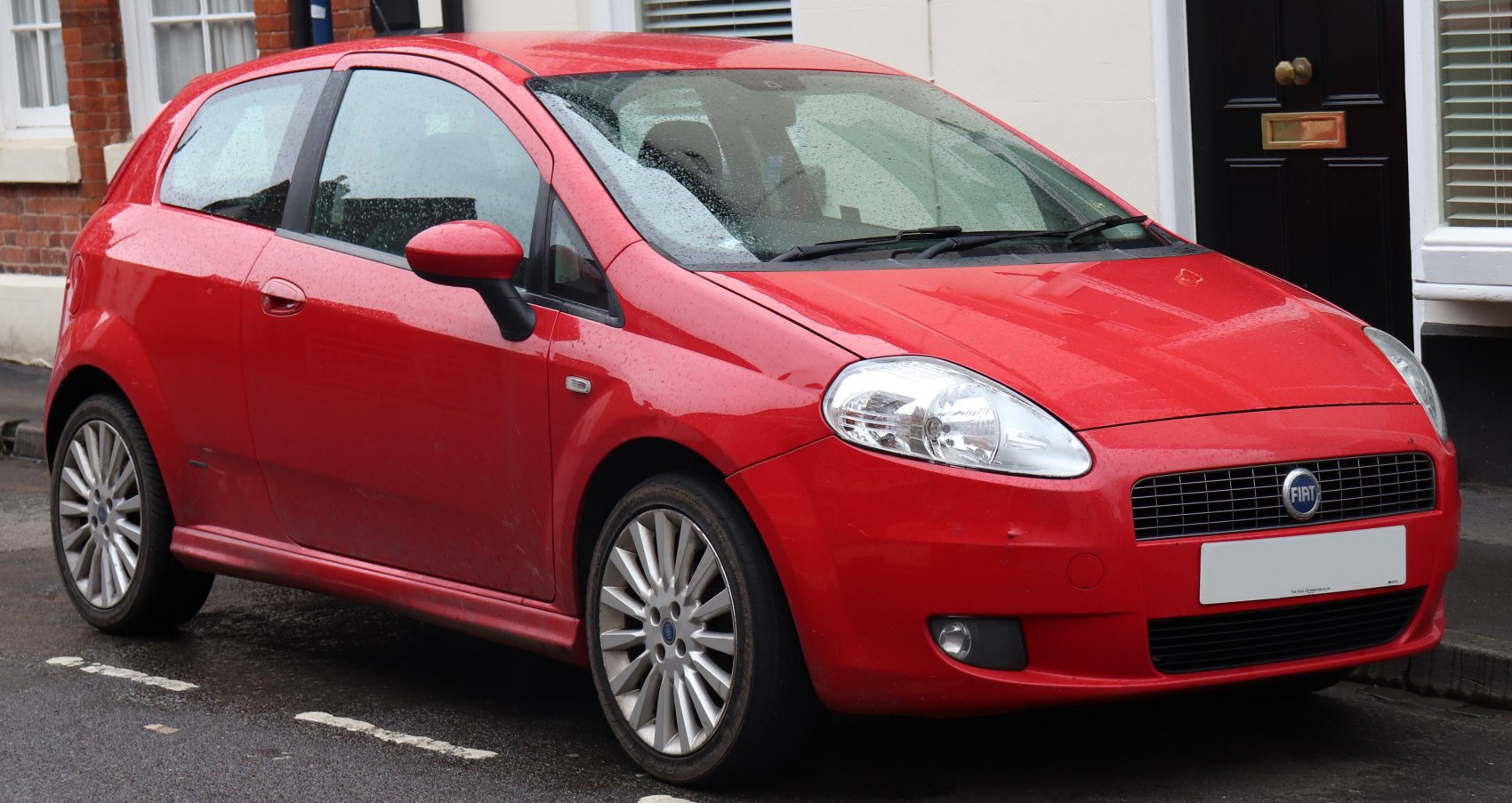 Red compact hatchback with rounded headlights and distinctive front grille