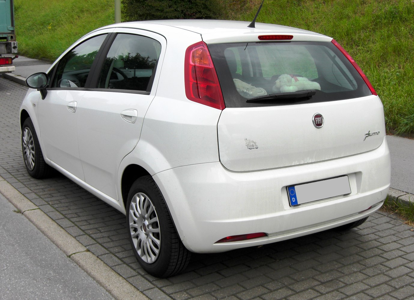 Rear and side view of a compact white hatchback with distinctive tall tail lights.
