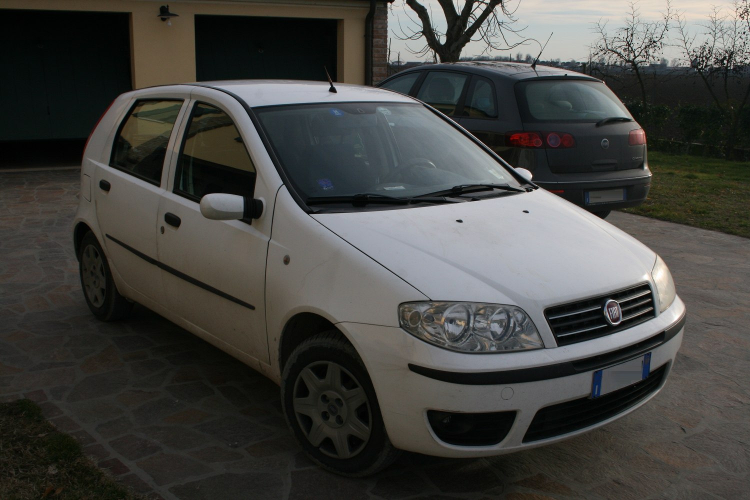 Front side view of a white 5-door hatchback with detailed headlights and grille.