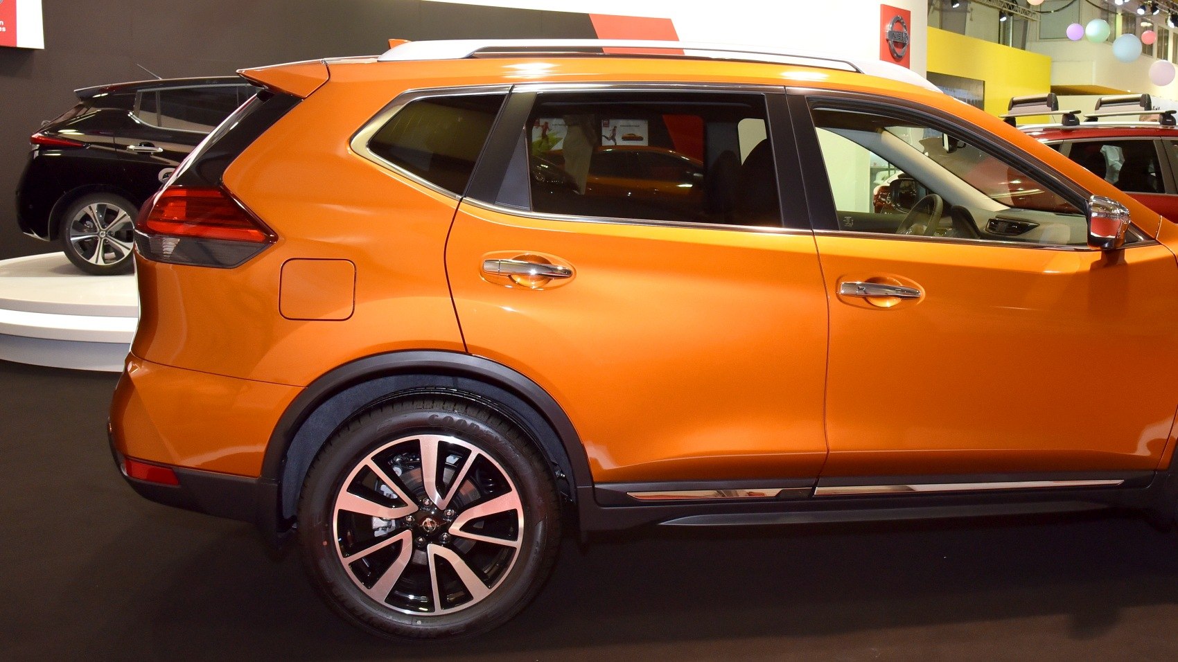 Rear side view of an orange SUV with alloy wheels and prominent window design