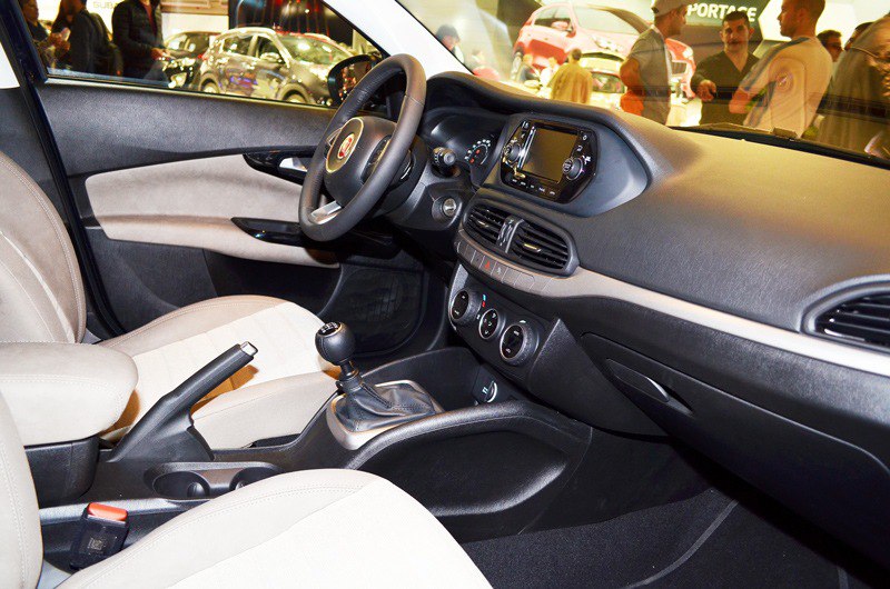 Car interior with dashboard, manual gear shift, and center console.