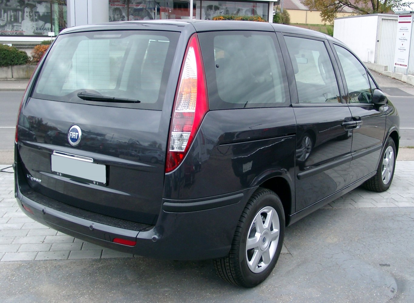 Rear-side view of black minivan with tall vertical tail lights and large windows